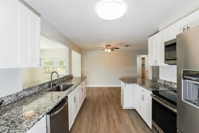 kitchen featuring white cabinetry, sink, stone countertops, appliances with stainless steel finishes, and light wood-type flooring