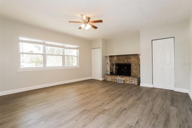 unfurnished living room with a stone fireplace, ceiling fan, and hardwood / wood-style flooring