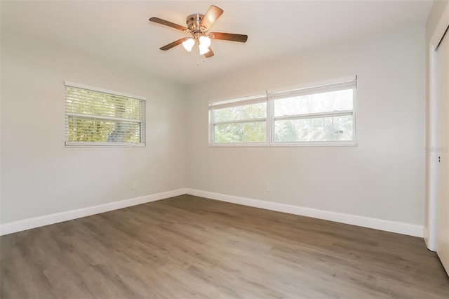 spare room featuring a wealth of natural light, ceiling fan, and dark wood-type flooring