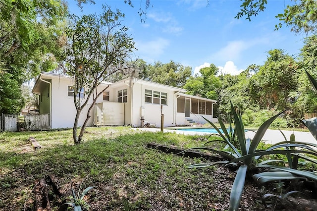 rear view of property with a fenced in pool and a sunroom