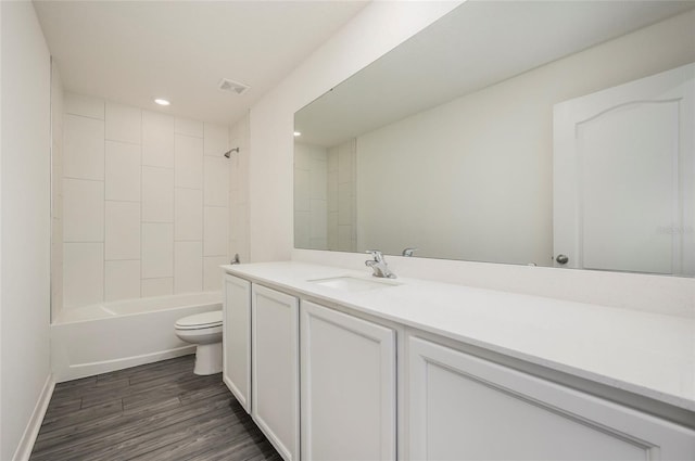 full bathroom with toilet, hardwood / wood-style floors, tiled shower / bath combo, and vanity