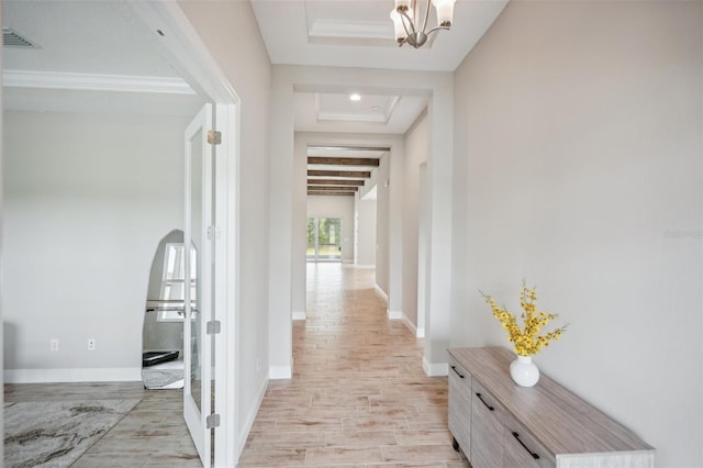 hall with a raised ceiling, beamed ceiling, light hardwood / wood-style floors, and an inviting chandelier