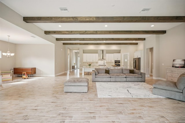 unfurnished living room featuring beam ceiling, sink, and an inviting chandelier