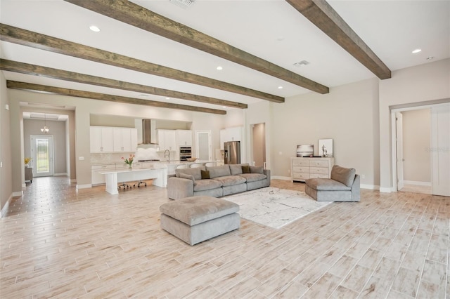 living room featuring beamed ceiling, light hardwood / wood-style flooring, and sink