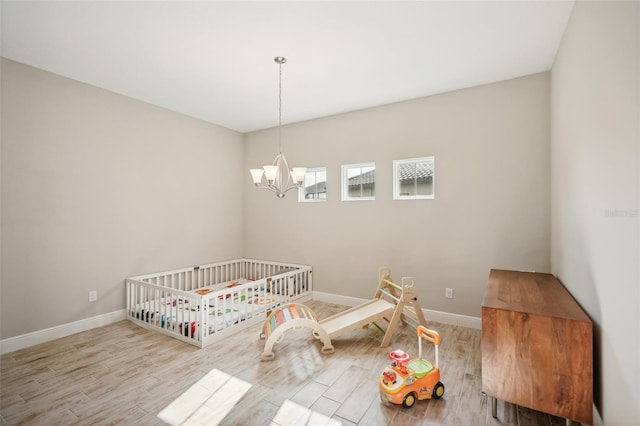 unfurnished bedroom with light wood-type flooring, an inviting chandelier, and a nursery area