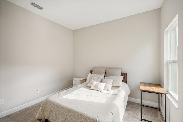 bedroom with light carpet and multiple windows