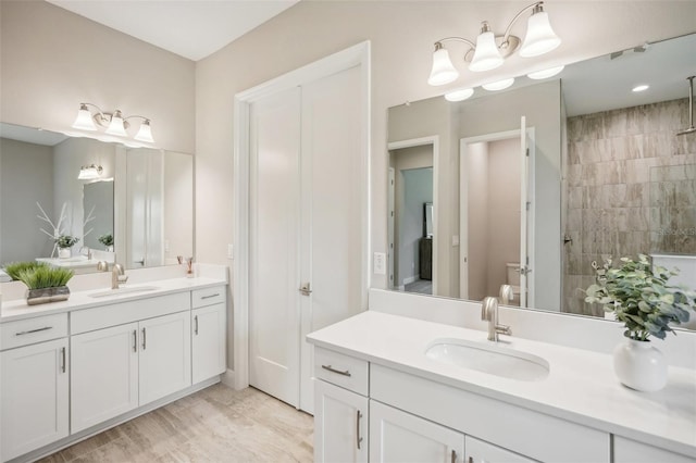 bathroom with a tile shower, vanity, and wood-type flooring