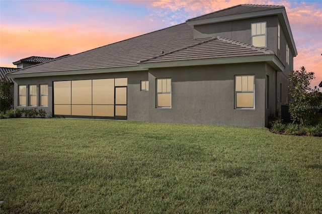 back house at dusk featuring a yard and central AC unit