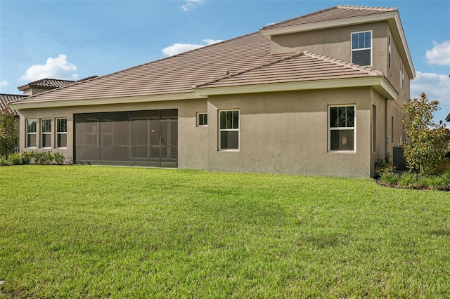 back of house with a sunroom, a yard, and central AC