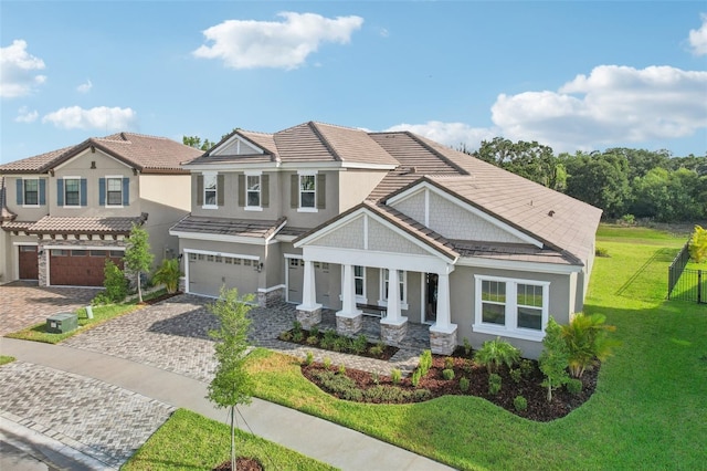 craftsman house with covered porch, a garage, and a front lawn