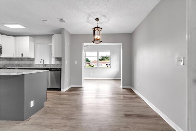 kitchen with light wood finished floors, stainless steel appliances, visible vents, backsplash, and white cabinetry