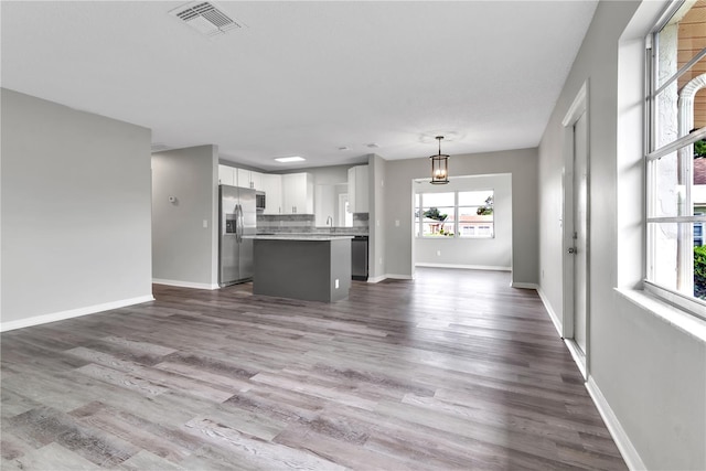 kitchen featuring visible vents, appliances with stainless steel finishes, open floor plan, a center island, and white cabinetry