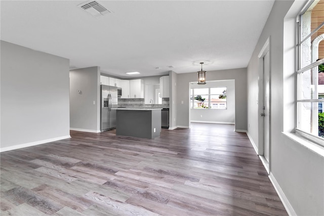 kitchen featuring dark wood-style floors, stainless steel appliances, visible vents, open floor plan, and a kitchen island