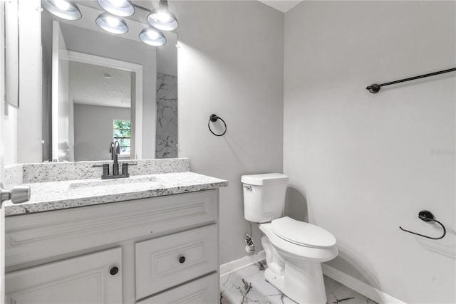 bathroom featuring marble finish floor, baseboards, vanity, and toilet