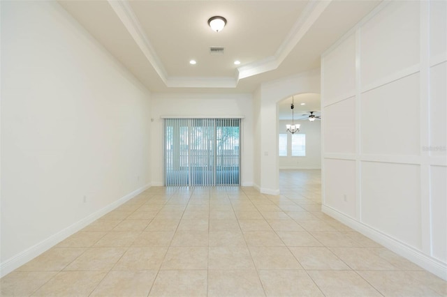 empty room featuring a tray ceiling, ceiling fan, ornamental molding, and light tile patterned flooring