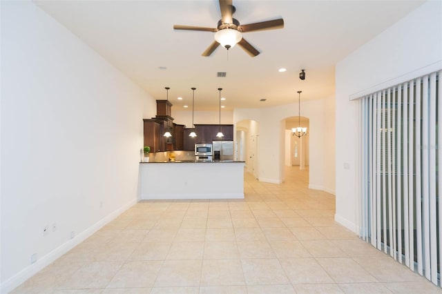 kitchen featuring kitchen peninsula, ceiling fan with notable chandelier, stainless steel appliances, pendant lighting, and light tile patterned flooring