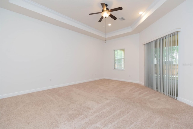 spare room with a tray ceiling, ceiling fan, carpet floors, and ornamental molding