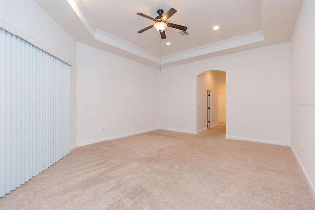 empty room with light colored carpet, a raised ceiling, ceiling fan, and ornamental molding