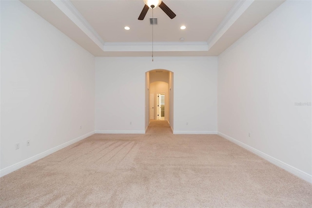 unfurnished room featuring ceiling fan, light colored carpet, ornamental molding, and a tray ceiling