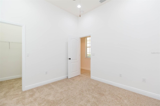 carpeted empty room with high vaulted ceiling