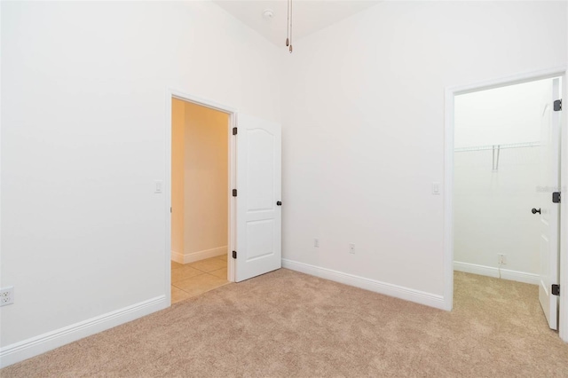 unfurnished bedroom featuring a walk in closet, light carpet, and a closet