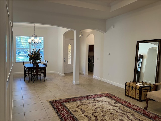 tiled dining room with washer and dryer and a chandelier