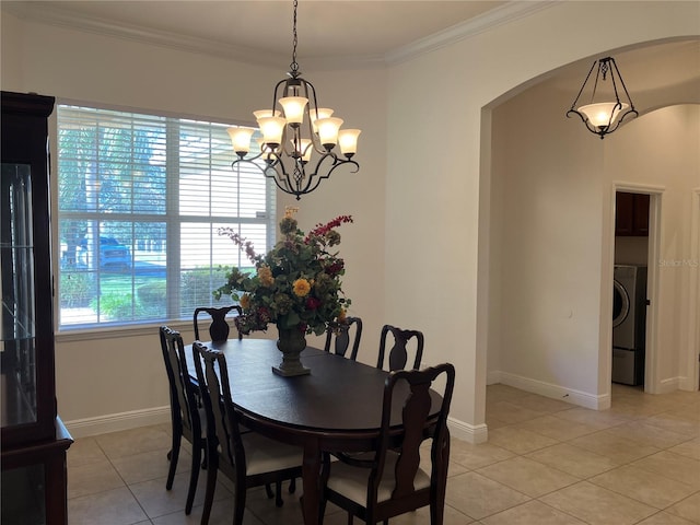 dining area featuring washer / dryer, light tile patterned floors, an inviting chandelier, and ornamental molding