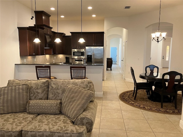 kitchen featuring pendant lighting, stainless steel appliances, light tile patterned floors, and a notable chandelier