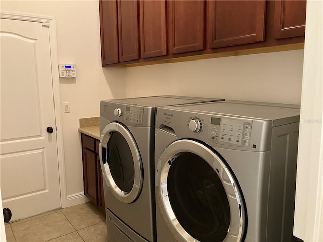 laundry room featuring cabinets, light tile patterned flooring, and washing machine and clothes dryer