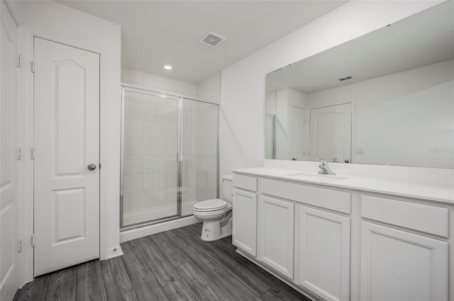 bathroom with vanity, toilet, wood-type flooring, and a shower with shower door