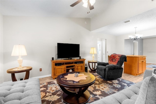 living room with ceiling fan with notable chandelier, lofted ceiling, a textured ceiling, and light hardwood / wood-style flooring