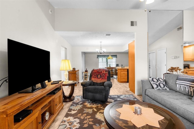 living room with ceiling fan with notable chandelier, light wood-type flooring, a textured ceiling, and high vaulted ceiling