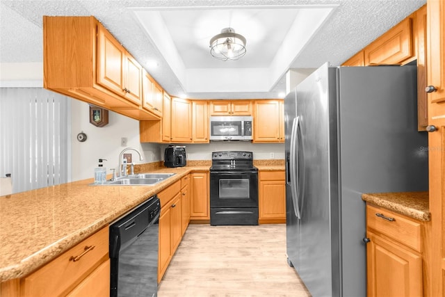 kitchen with sink, a raised ceiling, light hardwood / wood-style floors, a textured ceiling, and black appliances