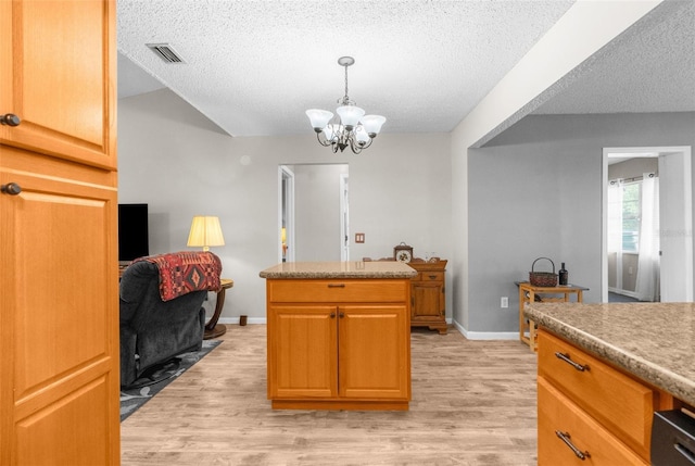 kitchen with a textured ceiling, a chandelier, light hardwood / wood-style floors, and decorative light fixtures