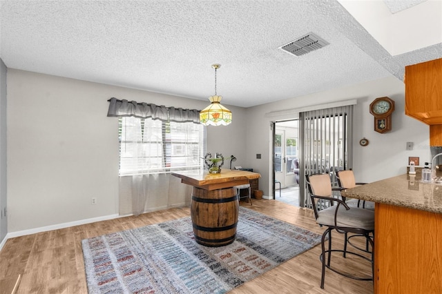 dining area with a textured ceiling and light hardwood / wood-style flooring