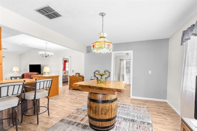 dining area featuring ceiling fan with notable chandelier, a textured ceiling, and light hardwood / wood-style flooring