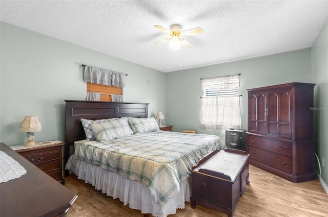 bedroom featuring ceiling fan, light hardwood / wood-style floors, and a textured ceiling