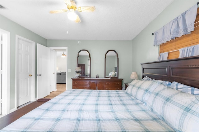 bedroom featuring hardwood / wood-style floors, ceiling fan, and a textured ceiling