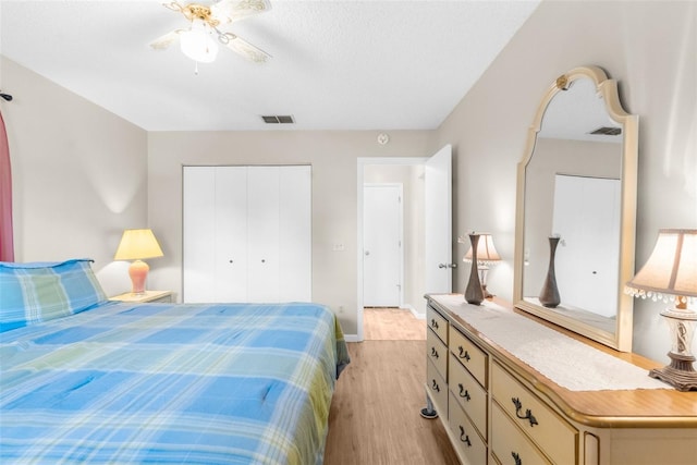 bedroom featuring ceiling fan, a closet, light hardwood / wood-style floors, and a textured ceiling