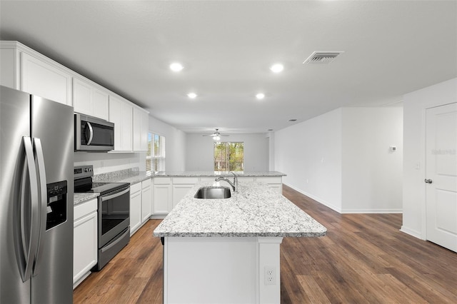 kitchen featuring a center island with sink, ceiling fan, light stone countertops, appliances with stainless steel finishes, and white cabinetry