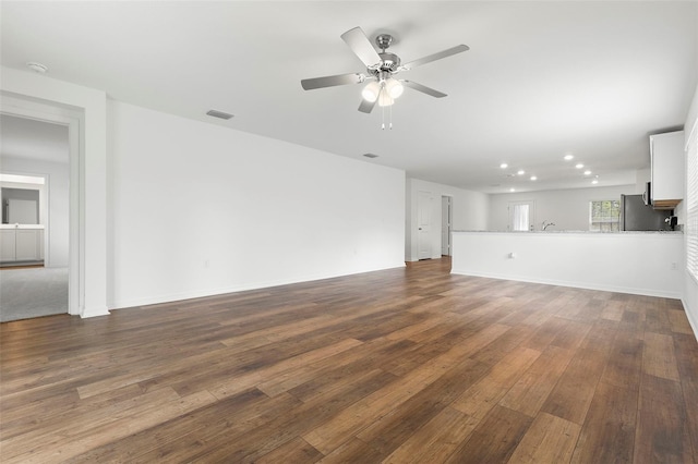 unfurnished living room featuring ceiling fan and dark wood-type flooring