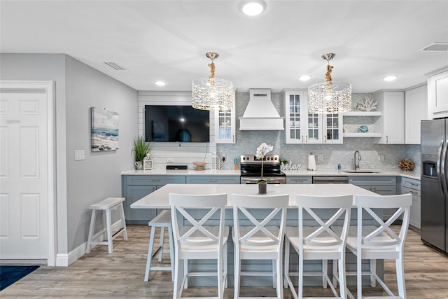 kitchen with pendant lighting, sink, stainless steel appliances, and custom range hood