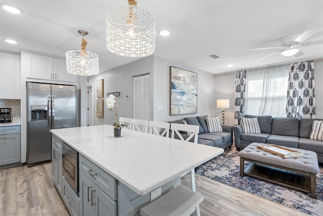 kitchen featuring pendant lighting, stainless steel appliances, a breakfast bar area, and gray cabinetry