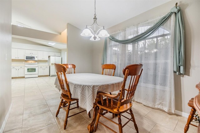 dining area with light tile patterned flooring, an inviting chandelier, and lofted ceiling