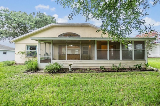 rear view of property with a sunroom and a lawn