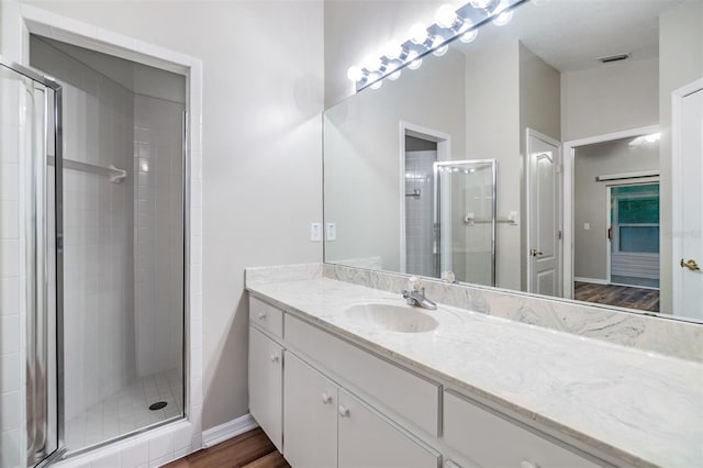 bathroom featuring hardwood / wood-style flooring, vanity, and an enclosed shower