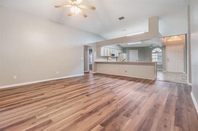 unfurnished living room featuring ceiling fan, lofted ceiling, and light wood-type flooring