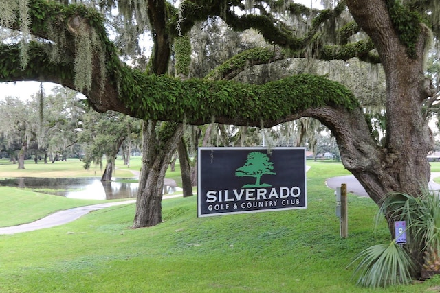 community sign with a water view and a lawn