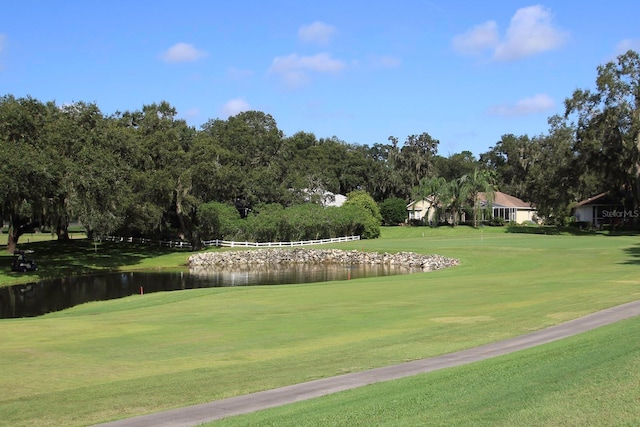 surrounding community with a water view and a lawn