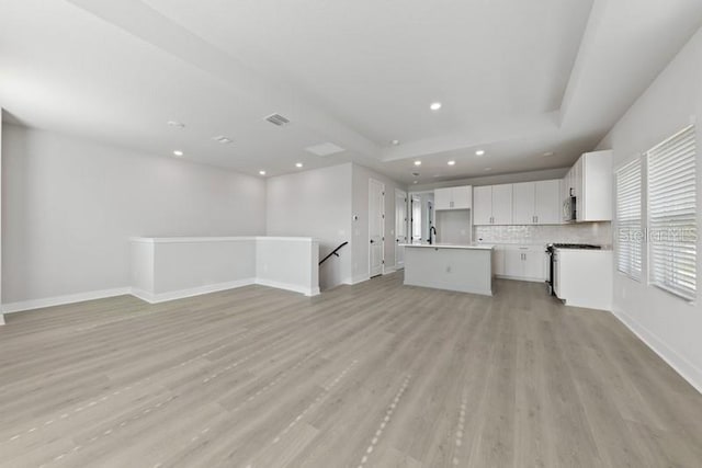 unfurnished living room featuring sink and light hardwood / wood-style flooring